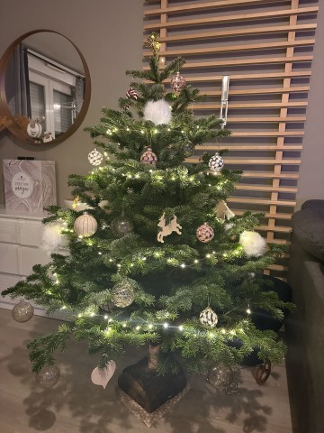 Pompons blancs, lumières douces et renne en bois. — Sapin Nordmann naturel